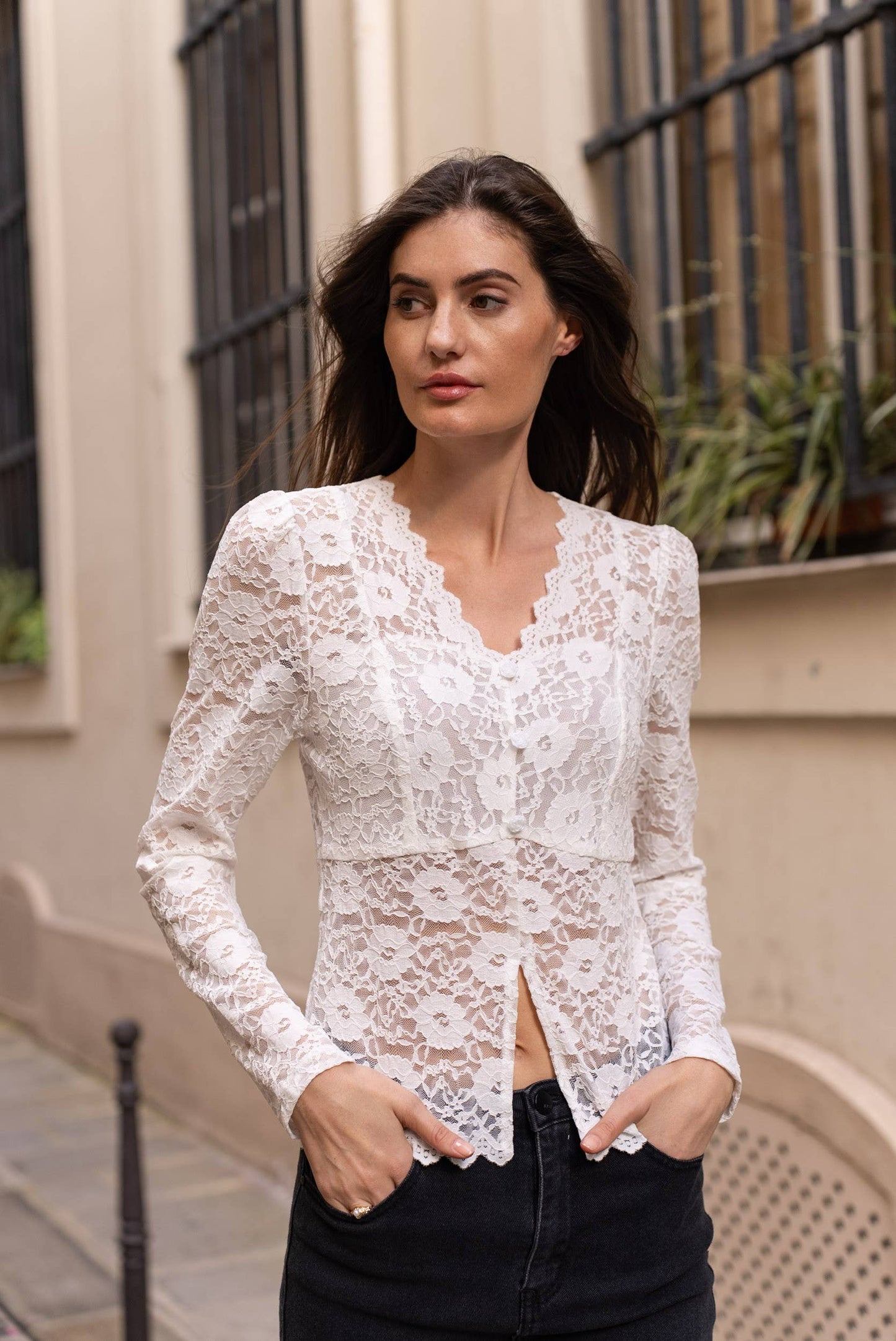 Woman in white lace blouse and black jeans.