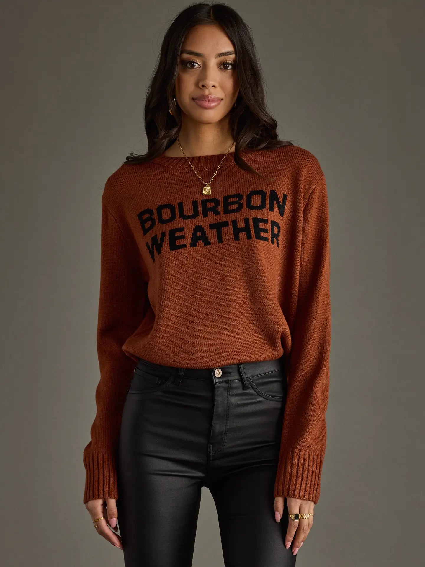 Woman wearing a brown sweater with Bourbon Weather and black pants.