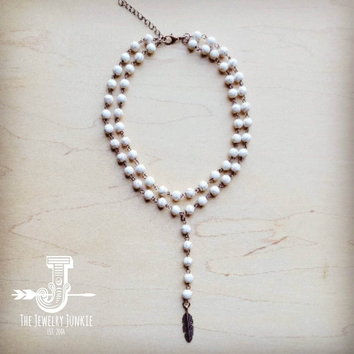 White beaded necklace with feather pendant.