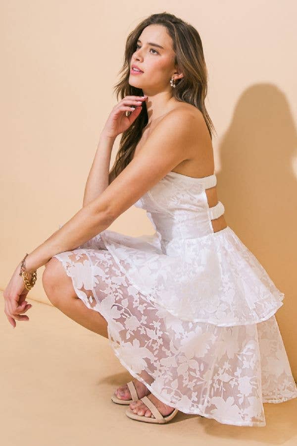 Woman in white floral dress, squatting.