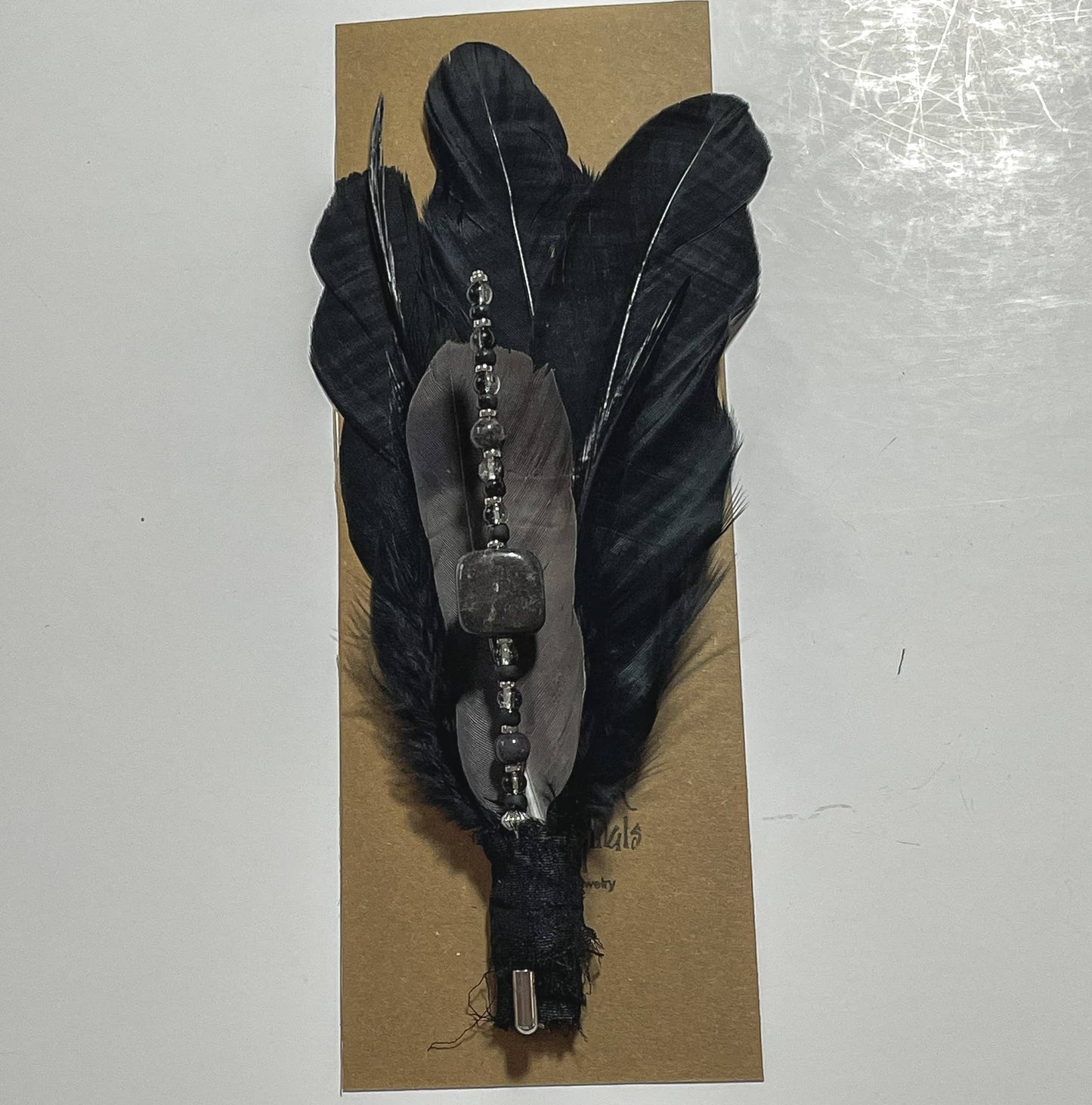 Black feather hair clip with beaded accent.