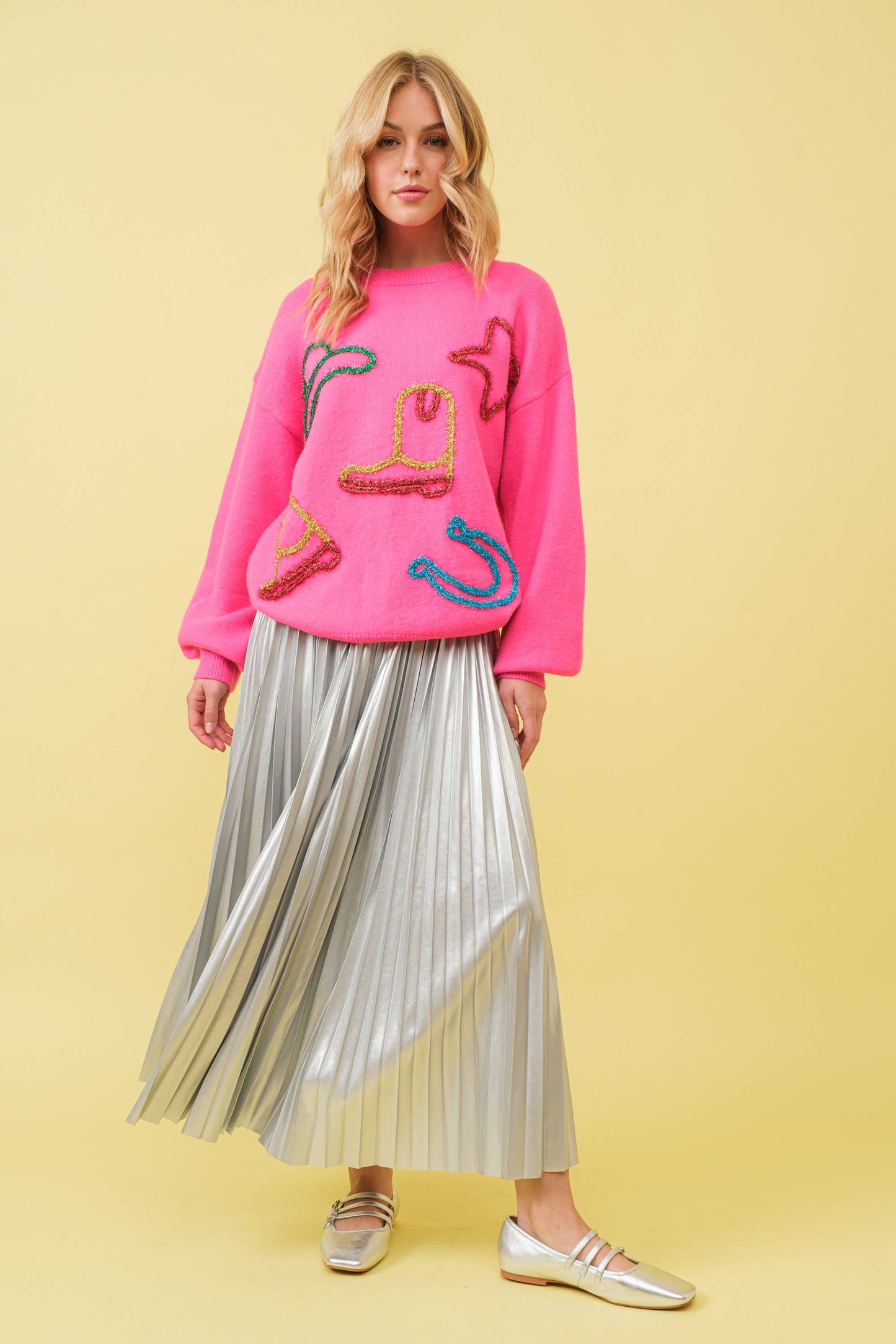Woman in pink sweater and silver pleated skirt.