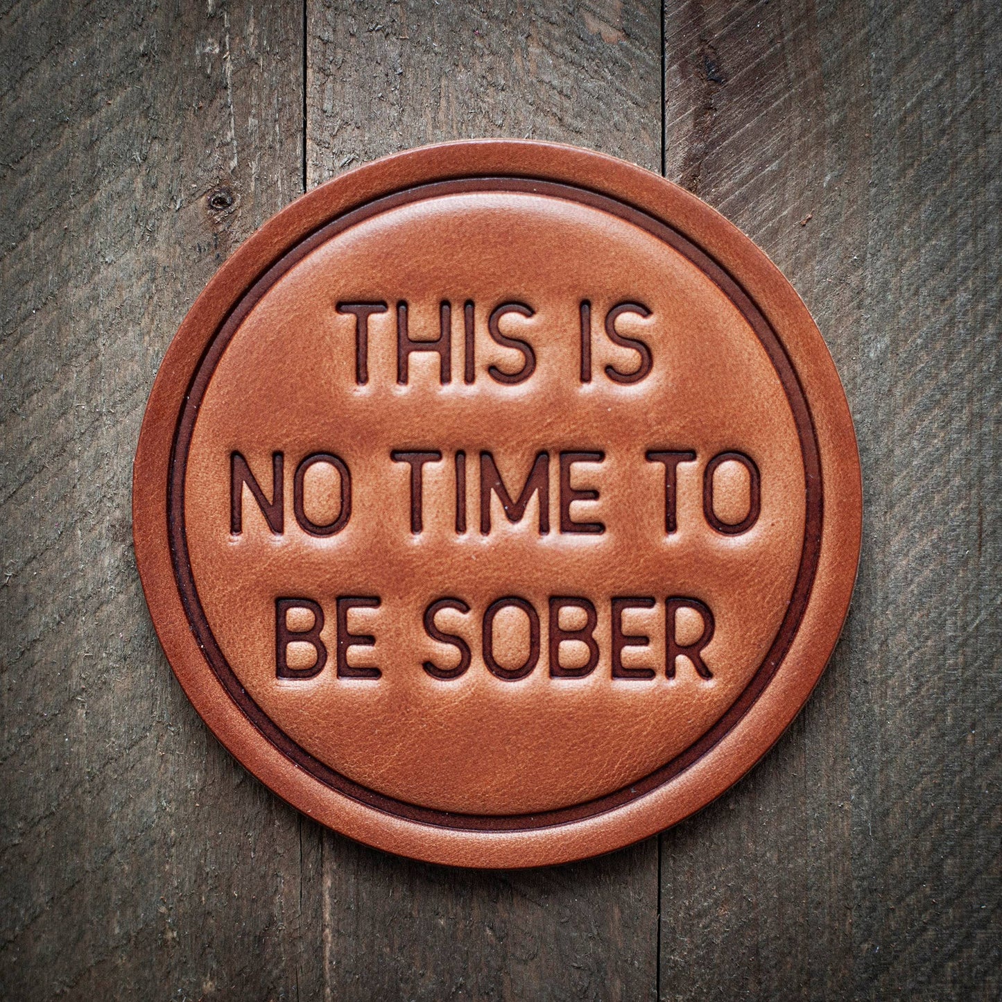 Brown leather coaster with text.