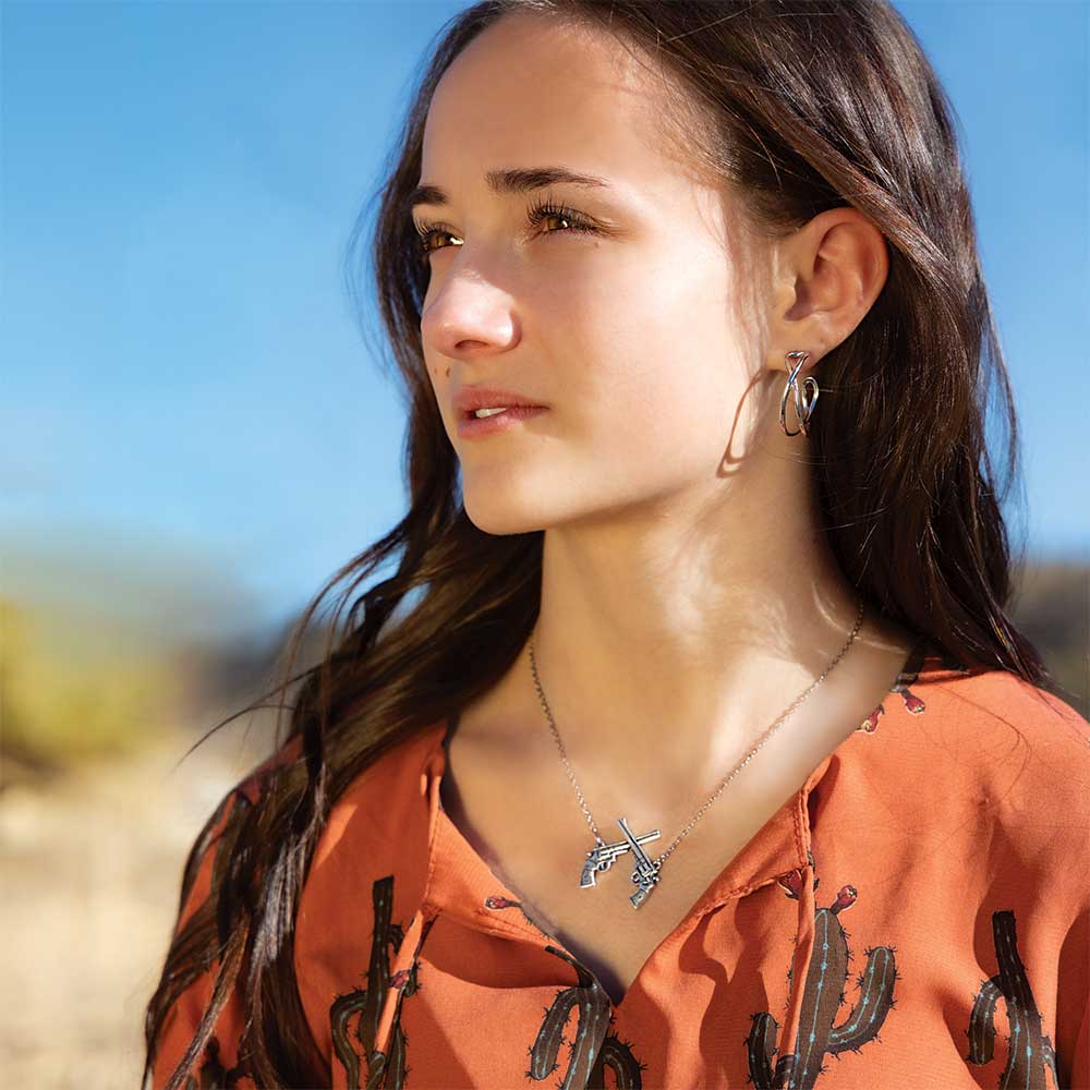 Woman with necklace in front of desert landscape.