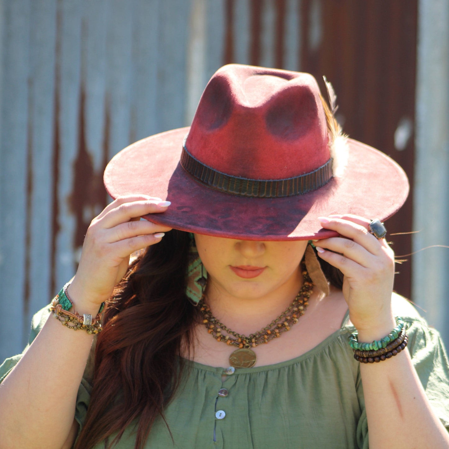 Woman wearing a red hat, holding it in front of her face.