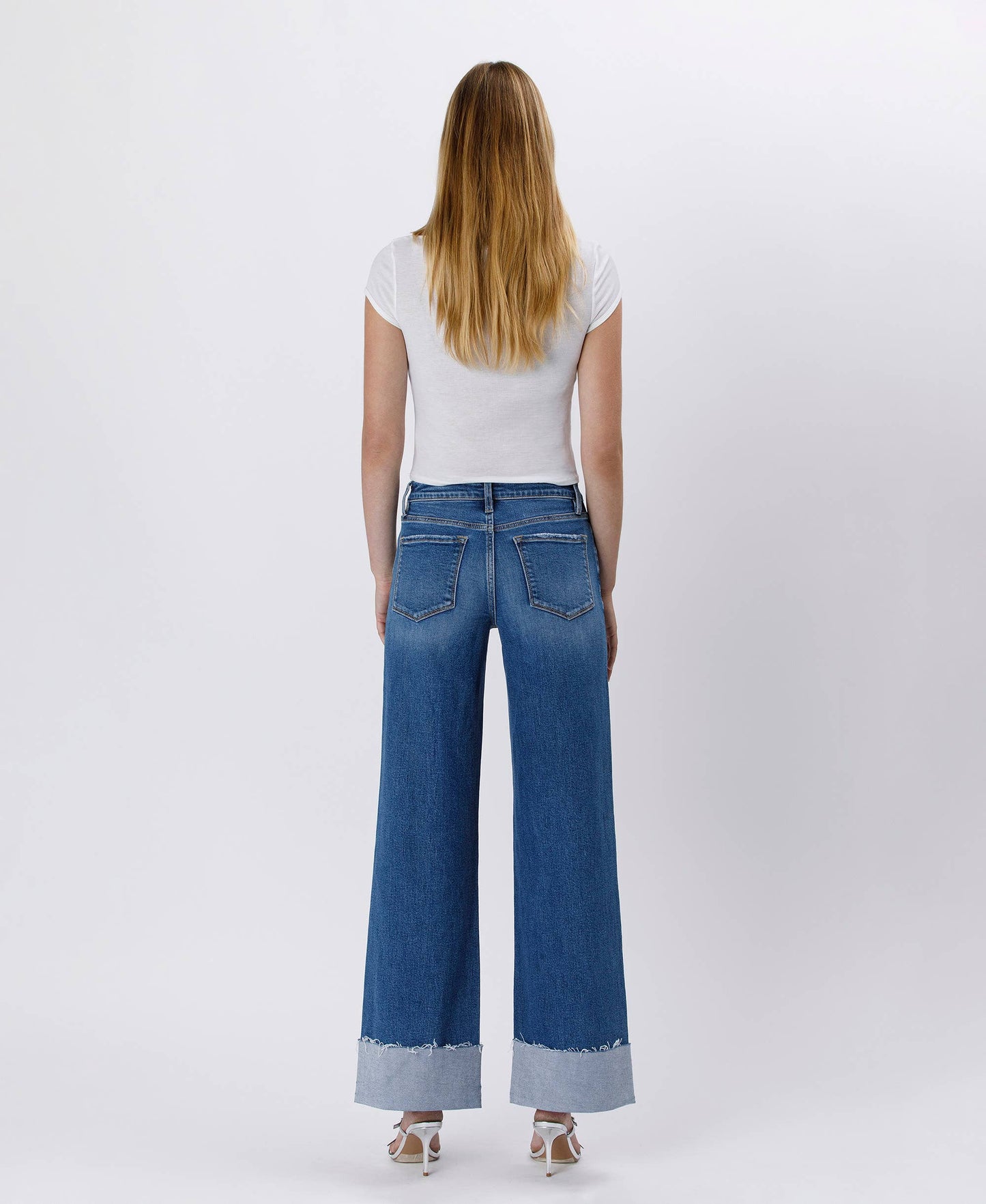 Woman in white top and wide-leg jeans from the back.