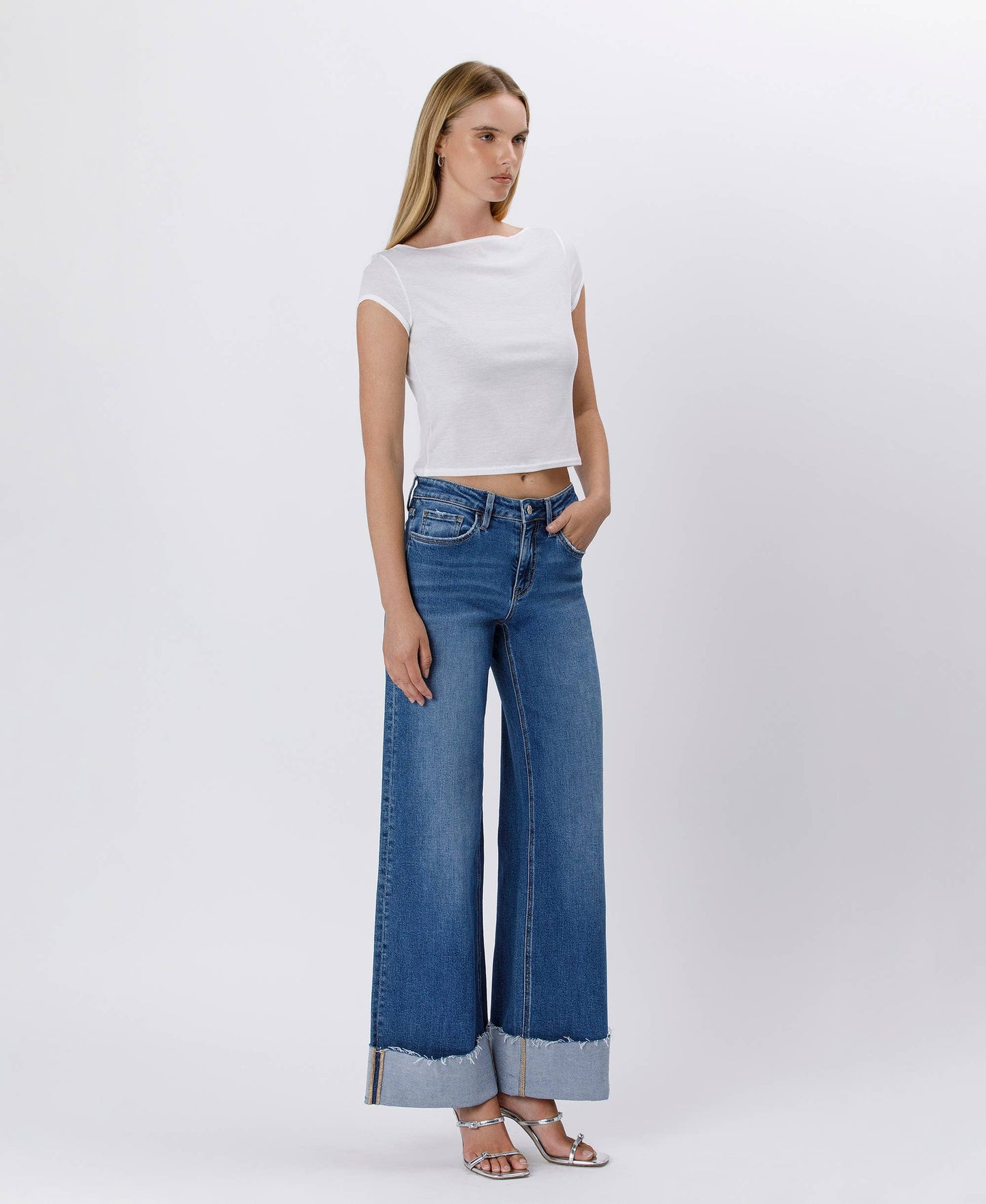 Woman in white top and wide-leg jeans.