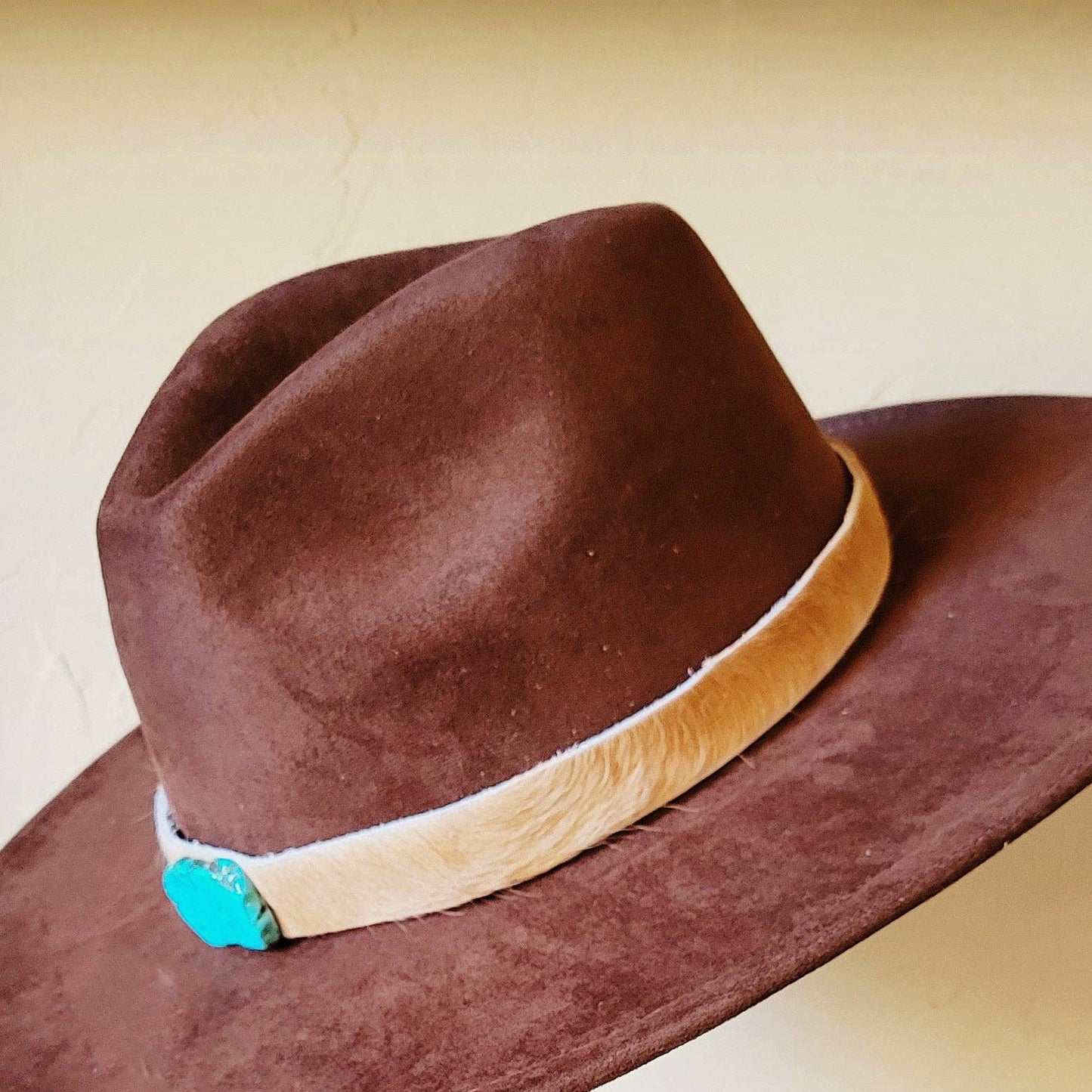 Brown cowboy hat with fur band and turquoise accent.