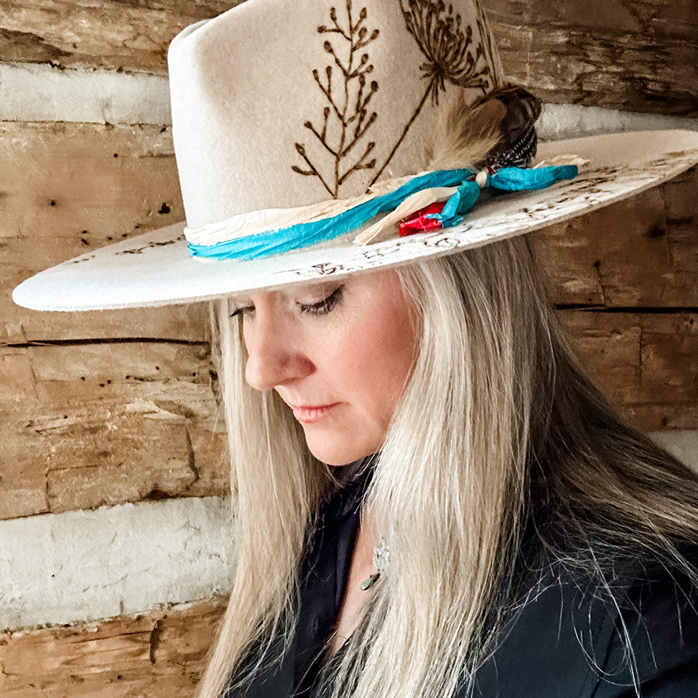 Woman wearing tan hat with feather and ribbon