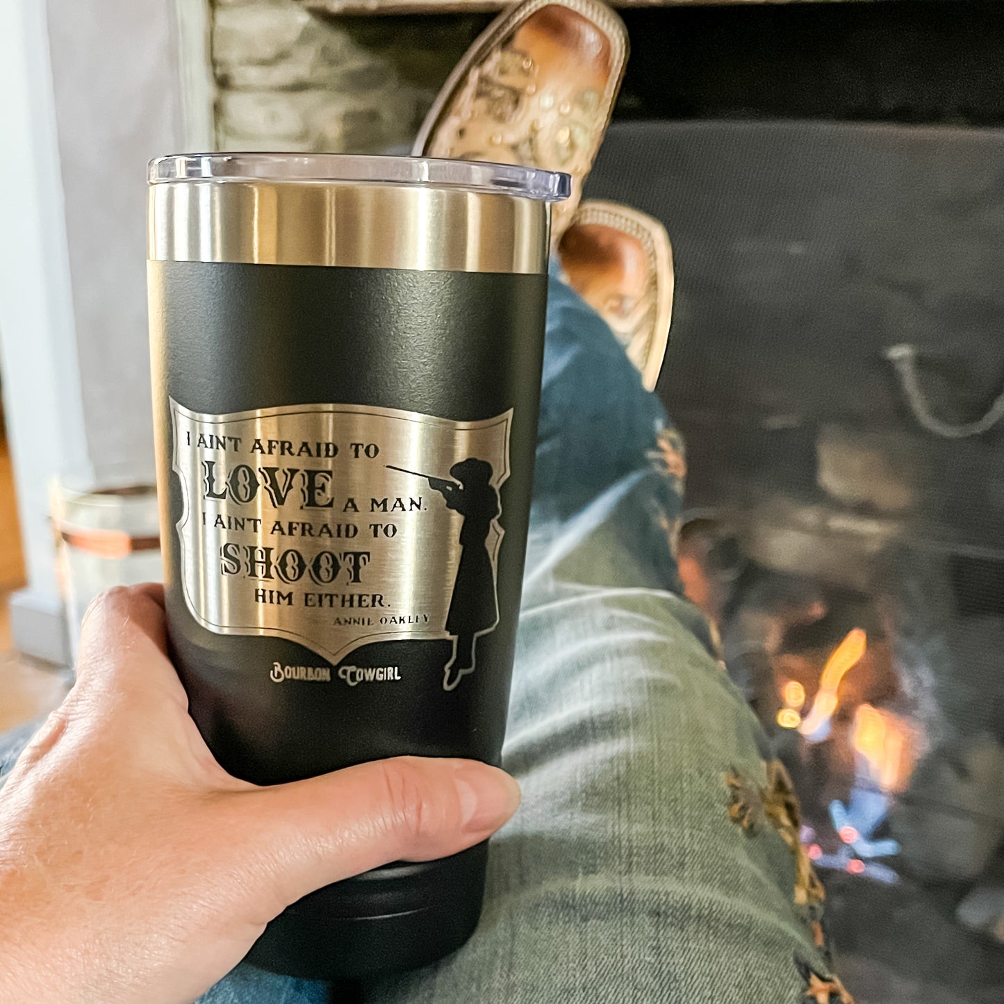 Person holding a black tumbler with etched design.