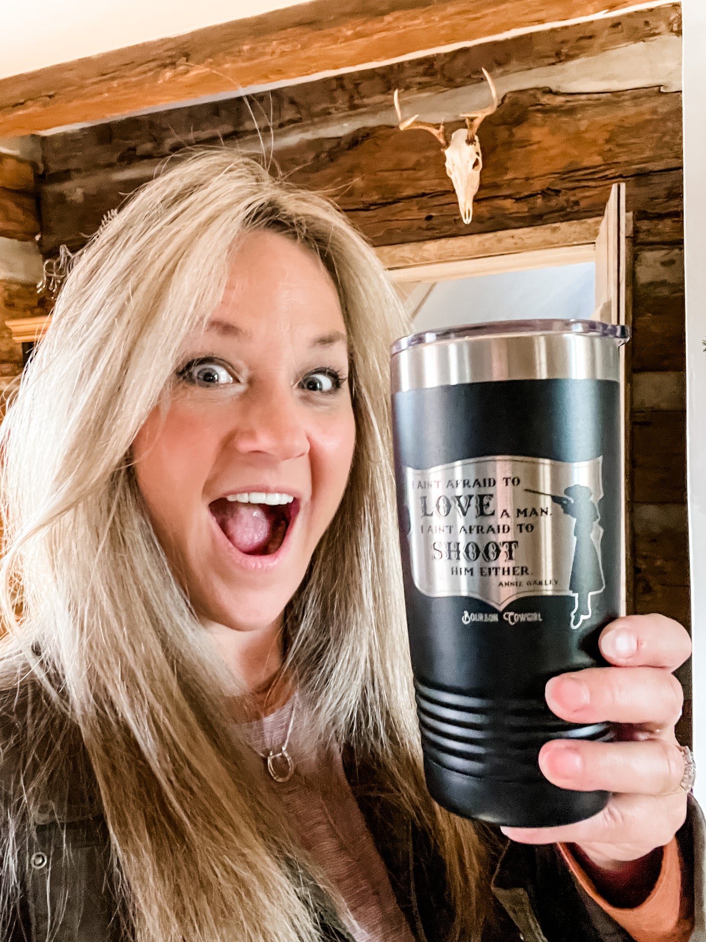Woman holding a black tumbler with text.