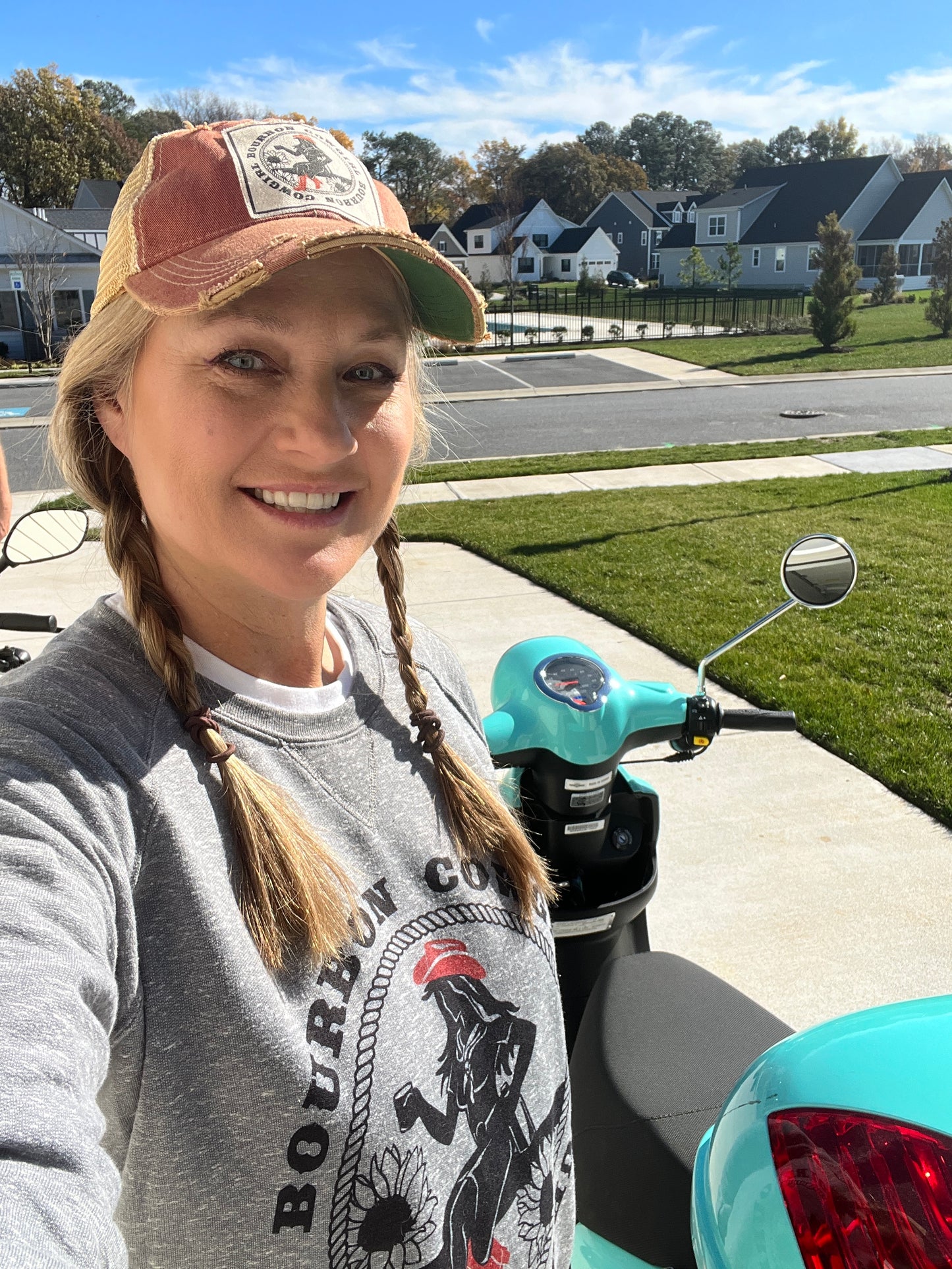 Woman in hat and braids, scooter in background.