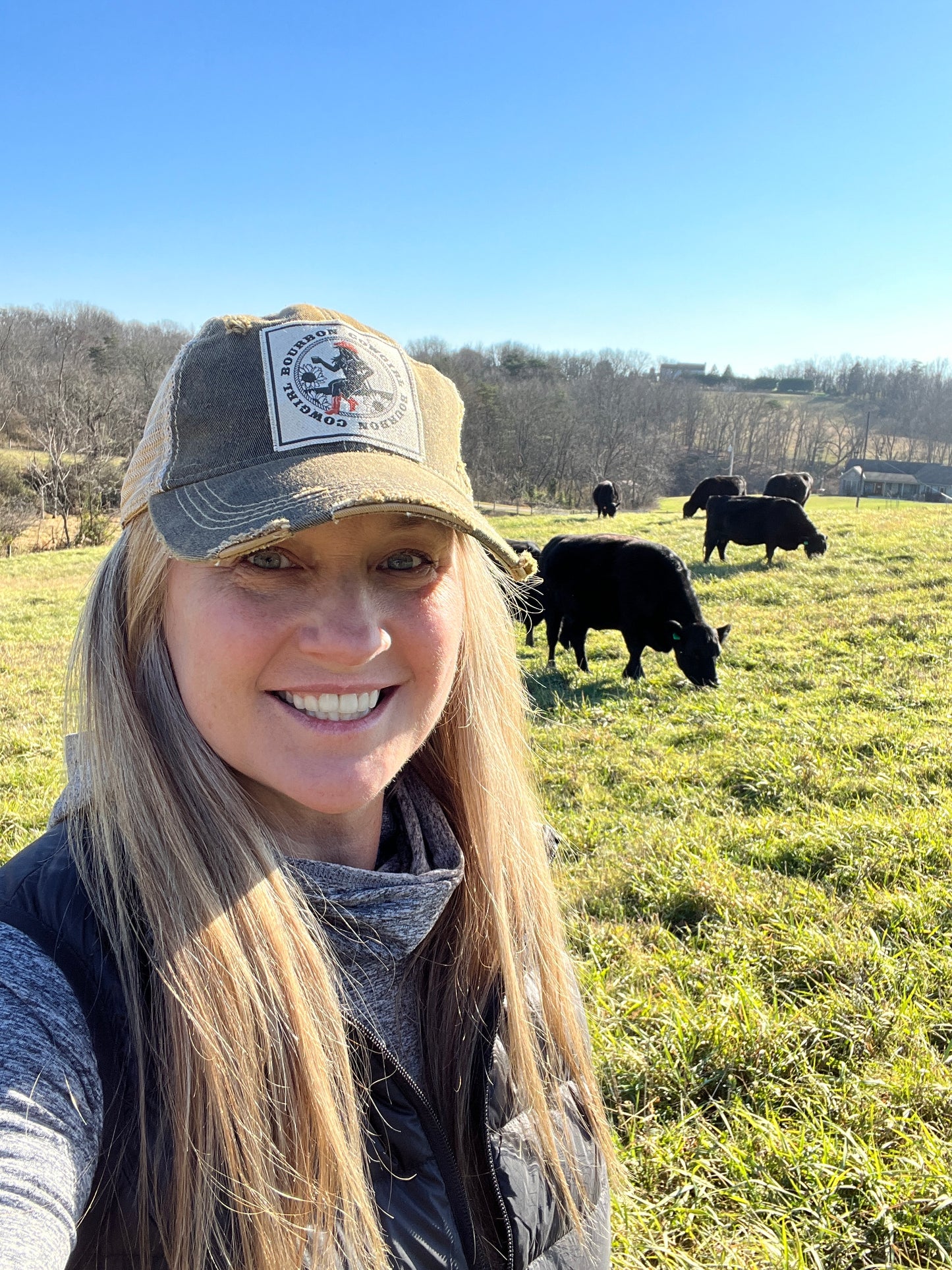 Woman smiling in a field with black cows.