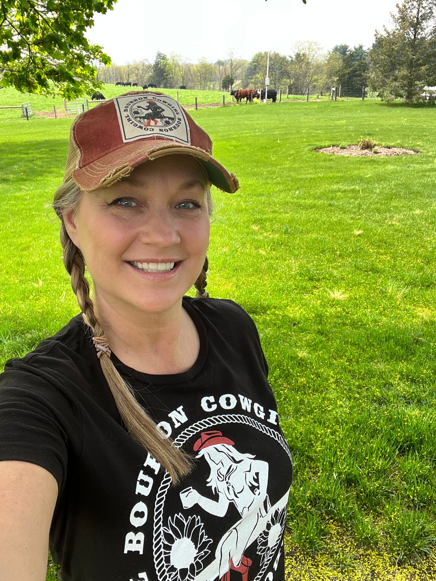 Woman in hat and shirt smiling in a field.