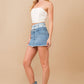 Woman in denim skirt, top, hat, and boots.
