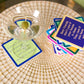 Martini with olive on a coaster next to a stack of quote coasters.