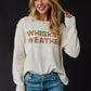 Woman wearing a cream sweater with Whiskey Weather text.