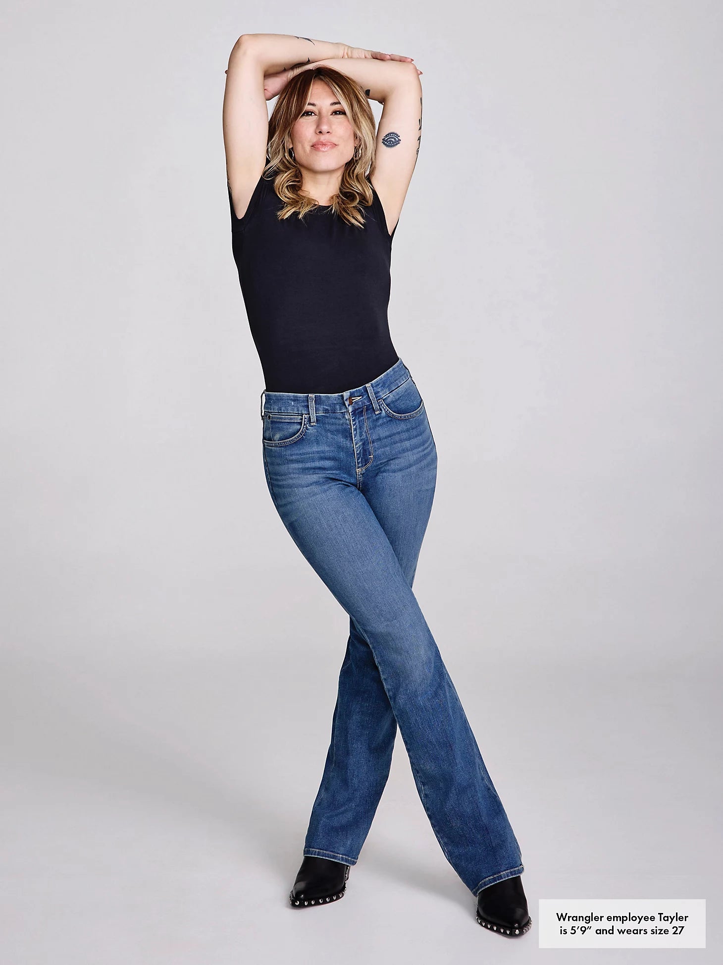Woman in black top and jeans, posing.