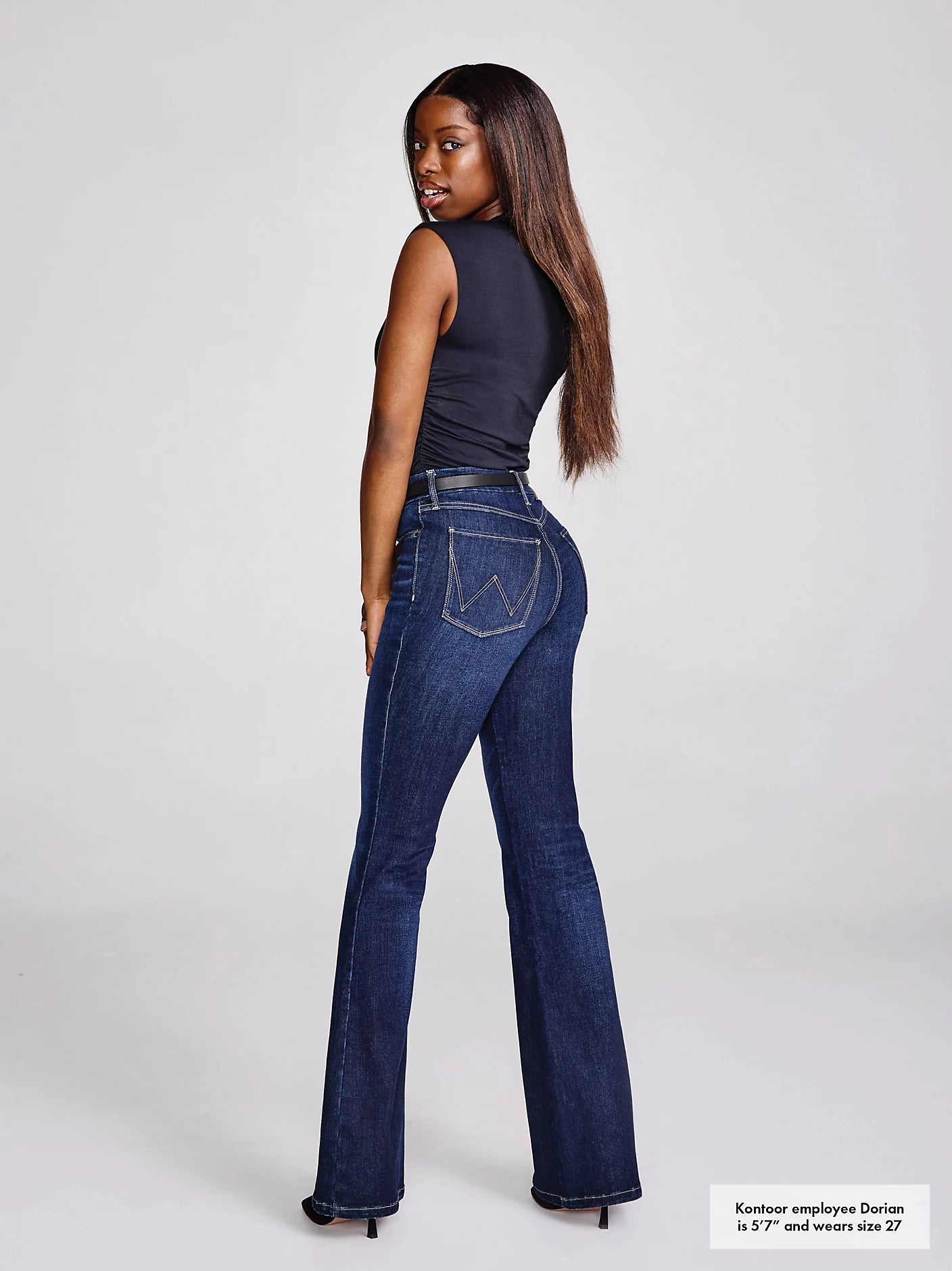 Woman in dark top and blue jeans.