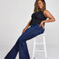 Woman in jeans sitting on a stool.