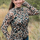 Woman in camouflage top smiling.