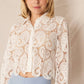 Woman in white lace shirt and blue pants.