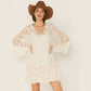 Woman wearing a white lace dress and brown cowboy hat.