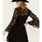 Woman wearing a black lace dress and hat.