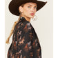 Woman wearing cowboy hat and horse-print jacket.
