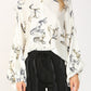 Woman wearing a white shirt with cat print and black pants.