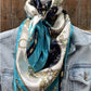 Silk scarf with blue, white, and gold nautical pattern on denim jacket.