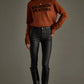 Woman in sweater, black pants, and boots.