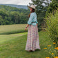 Woman in Toni Shirt and Sunny Skirt on a grassy hillside.