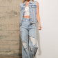 Woman wearing denim vest and ripped jeans.