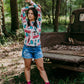 Woman in shorts and printed shirt near truck.