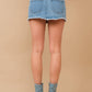 Woman wearing denim skirt and boots.