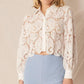 Woman wearing a white lace shirt and blue pants.