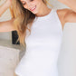 Woman wearing a white tank top and smiling.