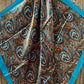 Paisley patterned scarf with blue border.