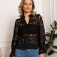 Woman wearing a black lace top and jeans.