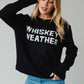Woman wearing black sweater with WHISKEY WEATHER text.