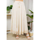 Woman wearing a long, cream-colored skirt with sandals.