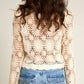 Woman wearing a crocheted jacket and jeans.