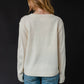 Woman in a cream sweater and jeans, viewed from the back.