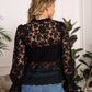 Woman in black lace blouse and jeans.