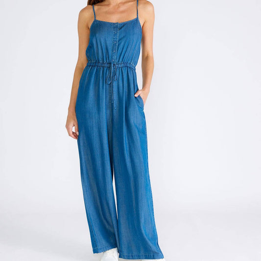 Woman wearing a blue denim jumpsuit.