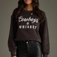 Woman in a sweatshirt that says Cowboys & Whiskey.