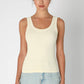 Woman wearing a cream ribbed tank top and jeans.