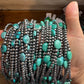 Hand holding turquoise and silver beaded bracelets.