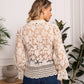 Woman in a white lace top and blue jeans.